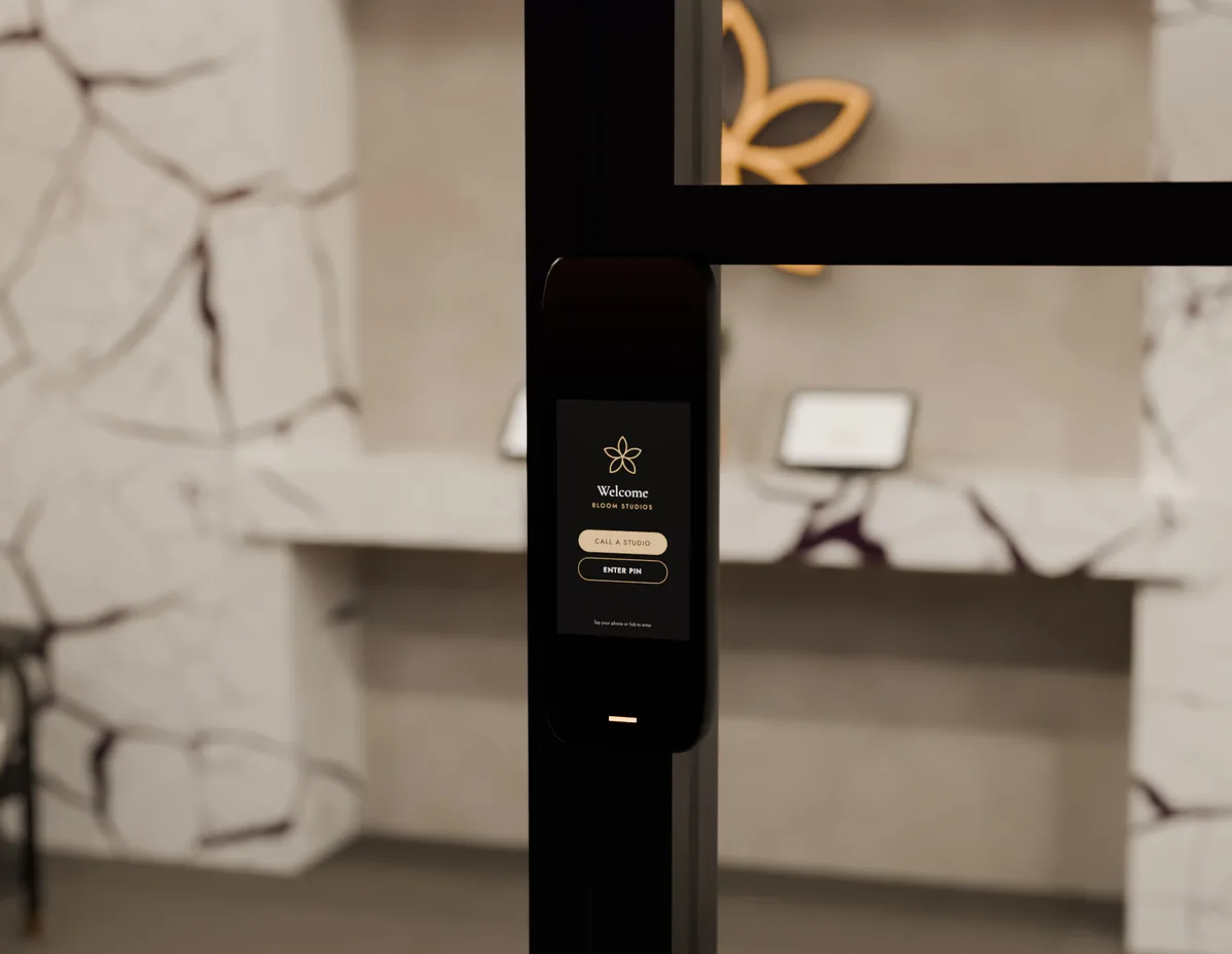 Render of the intercom beside the front entrance, its screen showing the Bloom flower with Call a studio and Enter PIN