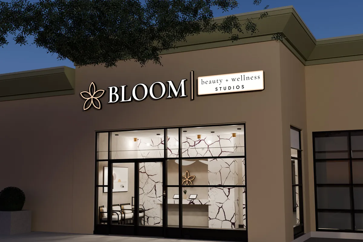 Render of the Bloom Studios storefront at Capri Centre at dusk, sign lit, reception visible through the glass